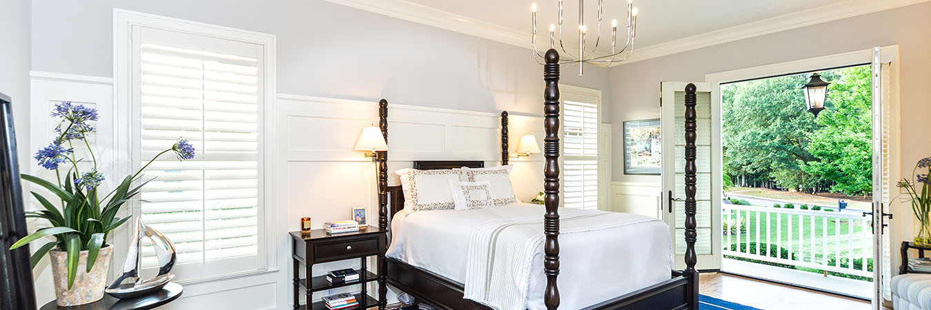 White Polywood shutters on windows and a door in a bedroom